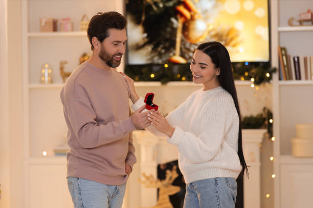 istock Making proposal. Man with engagement ring surprising his girlfriend at home on Christmas 1813699822