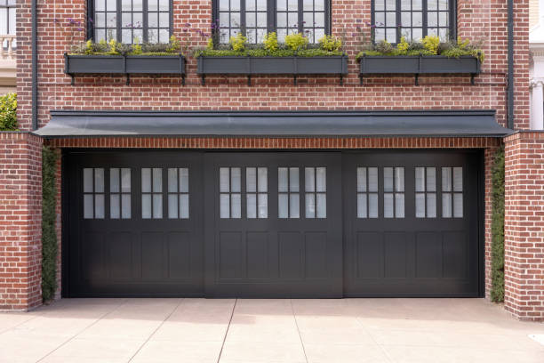 istock A house that has a brick facade lined with windows and potted plants with a three car garage. 1813718063