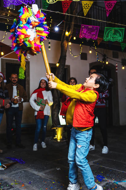 famiglia messicana che rompe una piñata alla tradizionale festa di posada per natale in messico america latina, ispanici - pinata mexico christmas mexican culture foto e immagini stock