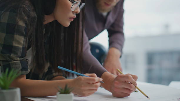 istock Closeup architects hands drawing at panoramic office. Serious man helping woman 1813763041