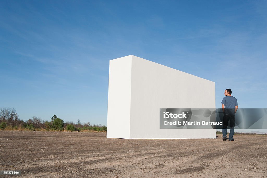 Homem de pé ao ar livre, olhando para parede branca - Foto de stock de 25-30 Anos royalty-free