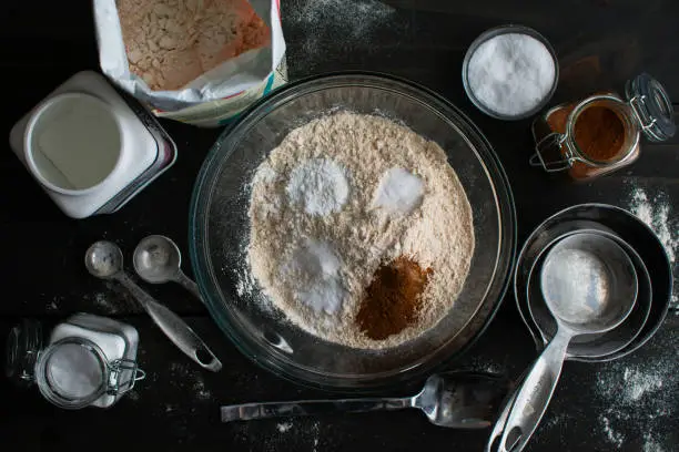 Whole-wheat pastry flour in a glass mixing bowl surrounded by kitchen tools and ingredients
