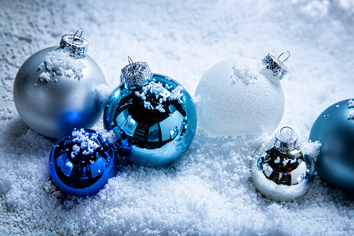 christmas tree decorations on blue sparkling background. silver balls, drum and blue small gift box.