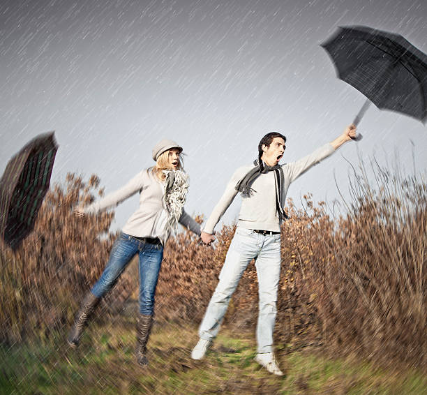 istock Woman and man with umbrellas during strong storm wind 181383939