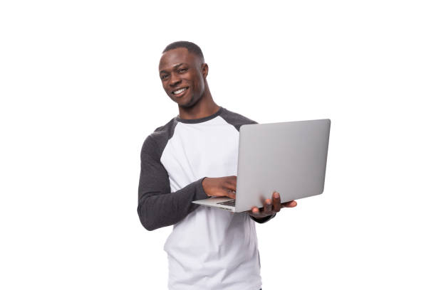 istock a young American guy dressed in a long-sleeved sweater holds a laptop for work in his hands 1813860842