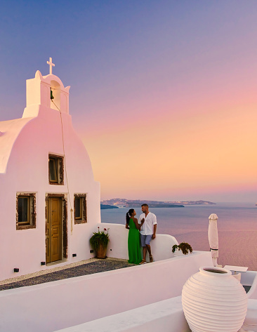 Couple hugging and kissing on a romantic vacation in Santorini Greece, men and women visit the whitewashed Greek village of Oia Santorini