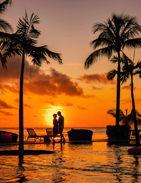 man and woman relaxing in a swimming pool, a couple on a honeymoon vacation in mauritius - honeymoon beach swimming pool couple imagens e fotografias de stock