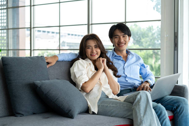 istock Young couple planning future together on couch with Laptop internet 1813861196
