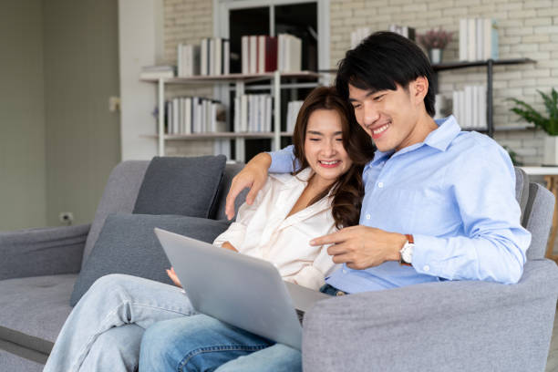 istock Young couple planning future together on couch with Laptop internet 1813861203