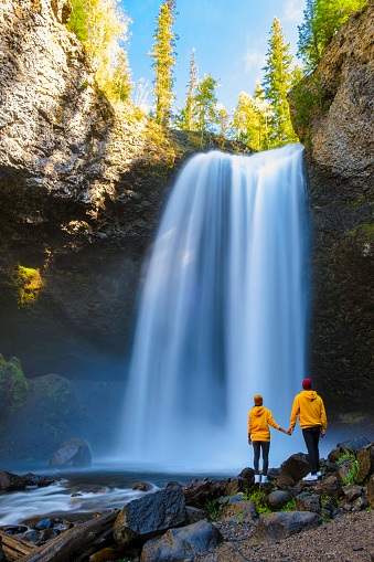 Moul Falls Canada is a Beautiful waterfall in Canada, A couple visits to Moul Falls the most famous waterfall in Wells Gray Provincial Park. a couple of men and women standing by a waterfall