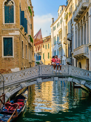 a couple of men and women on a city trip in Venice Italy sitting at a bridge in Venice, Italy. cityscape citytrip Venice Italy during summer