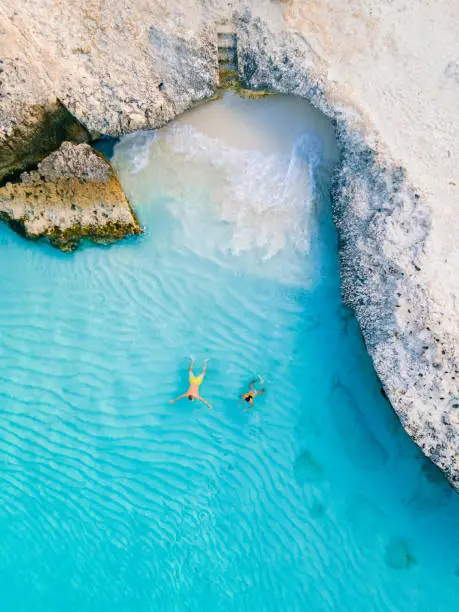 A couple of men and woman in a crystal clear ocean in the Caribbean, Tres Trapi Steps Triple Steps Beach, Aruba a popular beach among locals and tourists for diving and snorkeling,