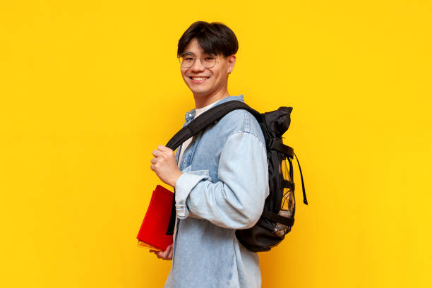 istock young asian guy student with backpack and books standing and smiling on yellow isolated background 1813883809