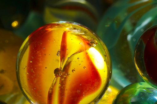 Colorful glass marbles with amber and dark green tones (Retouched and color manipulated, high magnification macro texture)