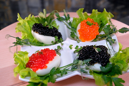 Put black caviar on an egg to serve delicious healthy food Halves of a hard-boiled chicken egg with red caviar on a wooden background.
