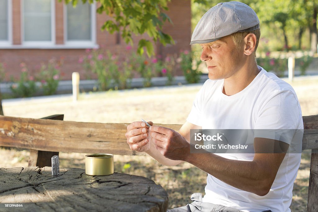 Uomo caucasico rolling sigaretta in un giorno d'estate - Foto stock royalty-free di Abuso di sostanze