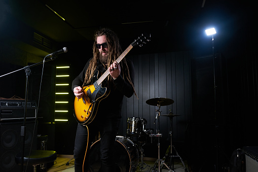 Guitarist man plays an electric guitar Close-up at studio.