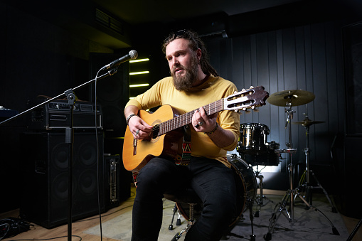 Guitarist man plays an acoustic guitar Close-up at studio.