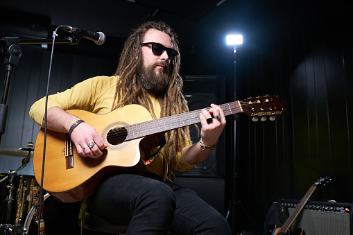 Guitarist man plays an acoustic guitar Close-up at studio.
