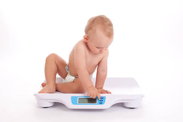 baby boy check own weight on scales stock photo