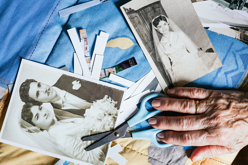 old woman's hand cutting out old photos for handicrafts.concept nostalgia and memories of the past.cutouts for old black and white photo album. do it yourself concept.couple in love on wedding day.