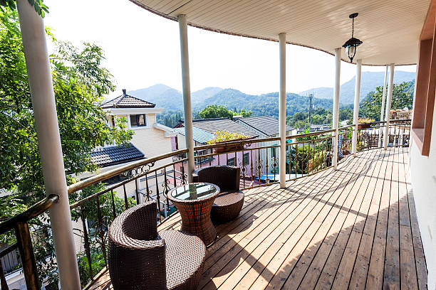 balcony or terrace with two wicker chairs and a potted plant, overlooking a mountainous landscape.