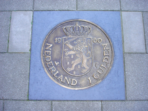 Former Dutch one guilder coin cemented in sidewalk