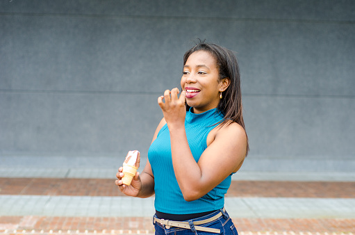 Portrait of happy black woman and eating ice cream cone for frozen dessert, cool snack and sweet food outdoor.