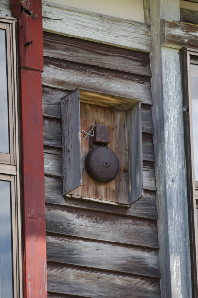istock Old rusty alarm on wooden school building wall 1814014138