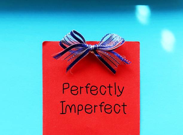 istock Red note with blue ribbon on blue background with handwritten text PERFECTLY  IMPERFECT, concept of accept yourself no matter what, with all flaws, imperfections make life interesting and help us grow 1814015767