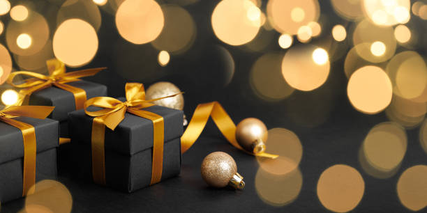 istock Black gift box with golden ribbon bow on black background 1814022522