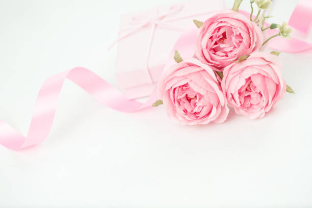 istock Three pink roses with ribbon and giftbox on the white table 1814022777