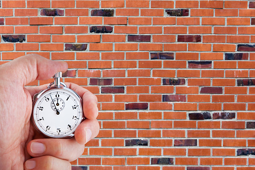 Stop Watch In Hand against brick wall