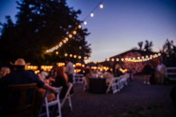 Outdoor Wedding Reception at Night Long exposure of an outdoor wedding ceremony at twilight and guests having a fun celebrating. Motion blur makes any people unrecognizable. Barn and string lights set the scene for the style. garden lights candle stock pictures, royalty-free photos & images