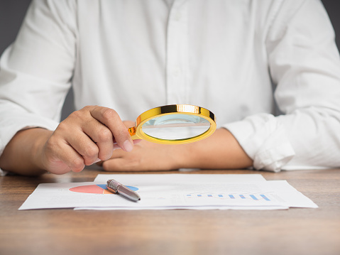 businessman examines statistical values with a magnifying glass