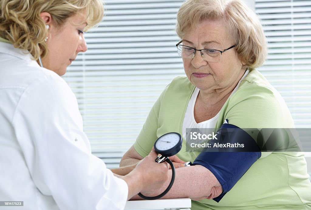 Medical exam Doctor measuring blood pressure of senior woman 70-79 Years Stock Photo