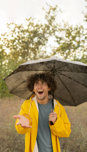 istock Arabic guy holding umbrella while strolling outside. He is looking at camera with true delight and sincere smile. 1814203688