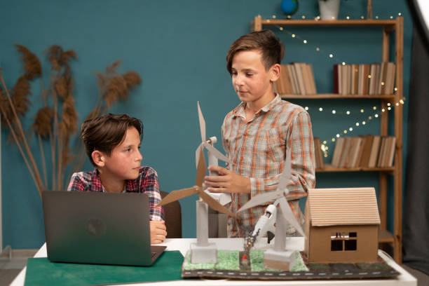 istock Two happy friends with laptop computer and wind turbine models at home making project. Renewable energy, children, technology and science 1814203713