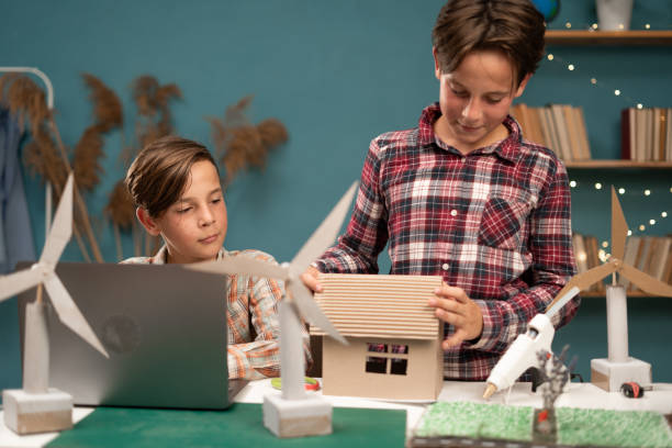 istock Happy children's with laptop computer making wind energy project and wind turbine models at home class. Renewable energy, science, and technology concept 1814203797