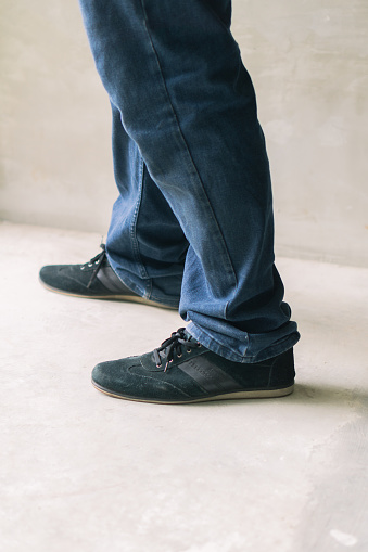 A mans denim-clad lower half with casual footwear. Fashion photo for men