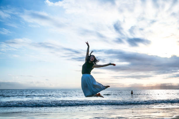 istock Beautiful lady jumping  at sunset beach side 1814277540