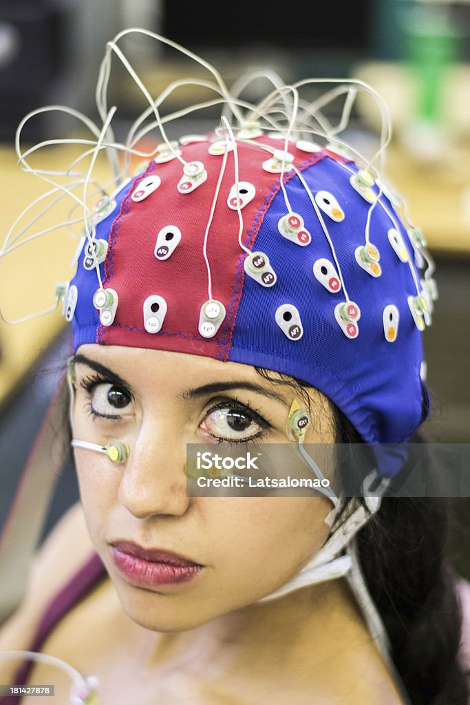 Psychophysiological measurements Picture of a latin girl with electrodes in her face, chest and head to record psychophysiological signals for research purposes. Electrocardiogram (ECG), electroencephalogram (EEG) and electrooculogram (EOG) being recorded. Adult Stock Photo