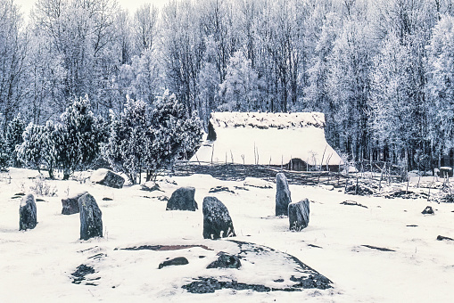 Åsarp, Sweden-01, 2020: Stone circle on a snowy meadow by a longhouse in a wintry landscape