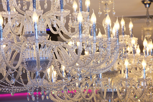 Ceiling chandelier of classic vintage style shape made of crystal and glass with candle shaped lamps.