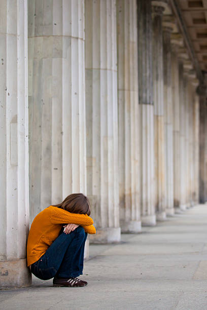 Sad girl is sitting near columns stock photo