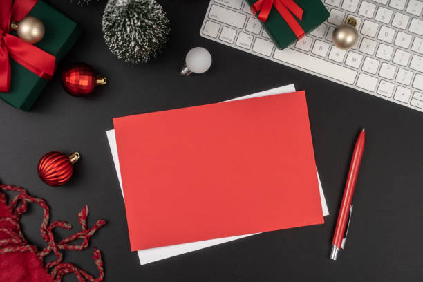 Empty paper blank for Christmas or New year greeting card. Gift boxes, holiday decorations on black background top view. Flat lay style.