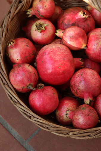 Close-up of red ripe Pomegranate fruits in a wicker basket. Punica granatum
