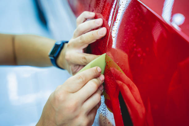 The process of installing protective film on the new red car. The process of installing protective film on the new red car. vehicle wrap stock pictures, royalty-free photos & images