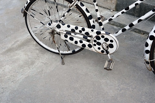 Old bicycle spot black on white color stay on the concrete floor, vintage concepts.