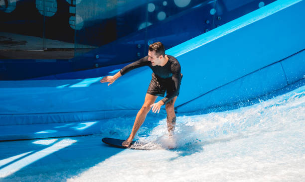 istock Young man surfing on a wave simulator at a water amusement park 1814380254